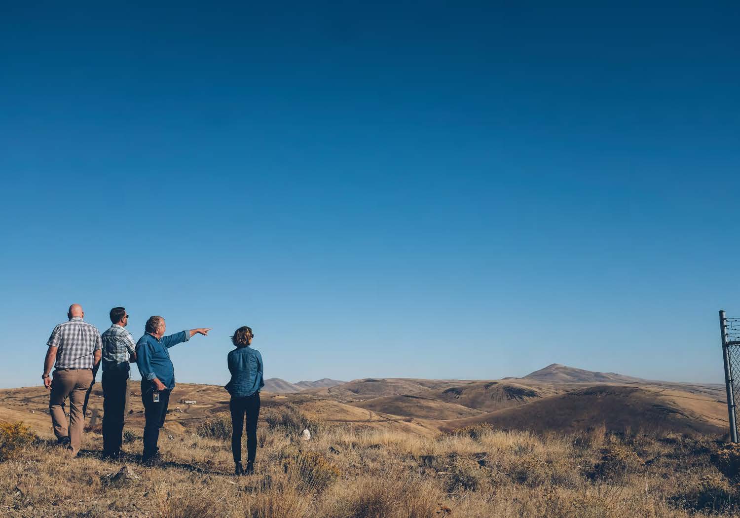 artists with dot staff on open plains pointing away at mountains